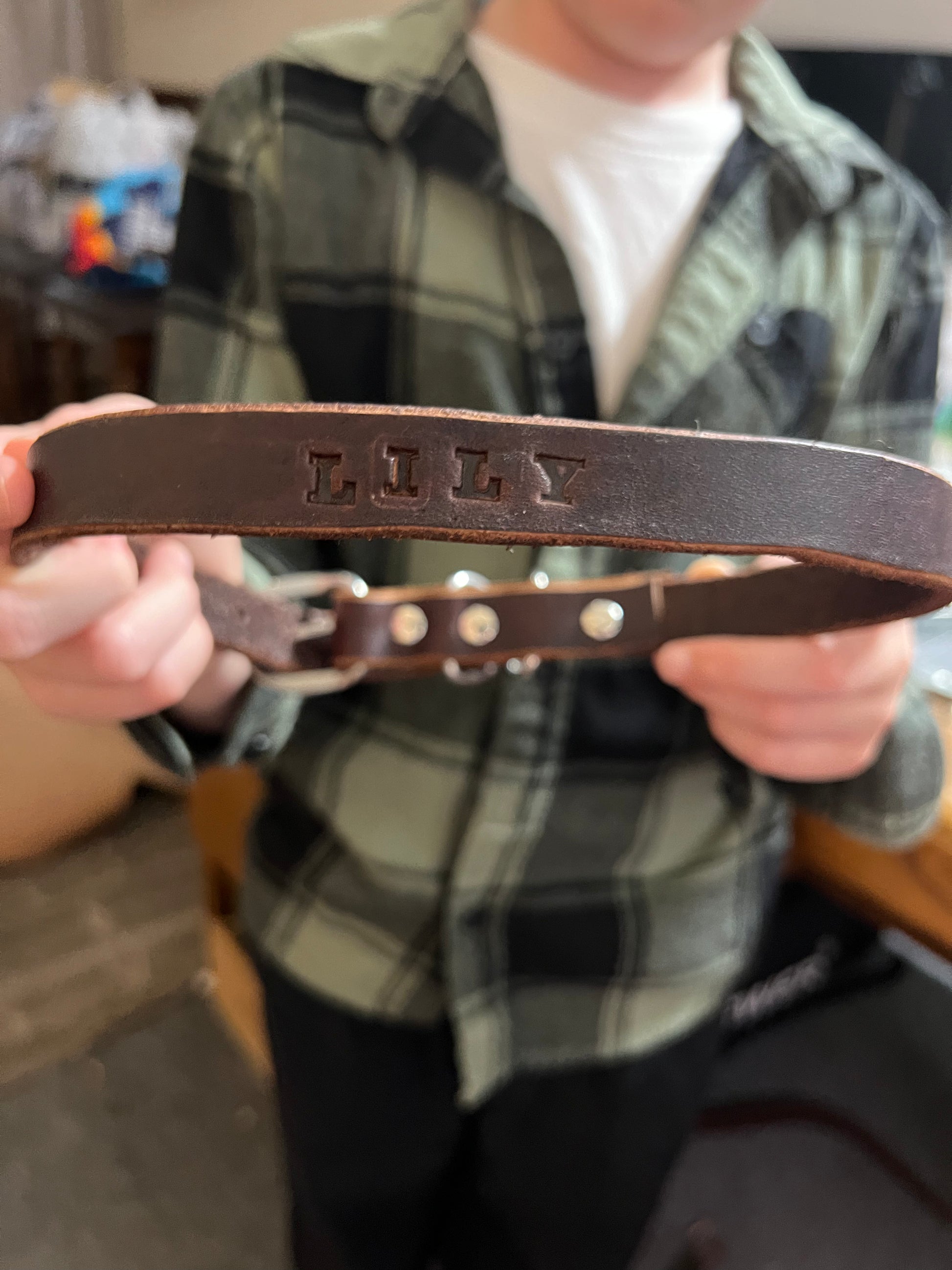 Boy holding custom leather dog collar he made to raise money for charity.